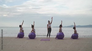 Footage B roll 4k shot Athletic group of women practicing yoga position with yoga ball at beach. Fitness training outdoor stretching body at morning. Morning yoga practice soft sunlight on the beach.