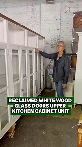 Reclaimed upper kitchen cabinet unit made of white painted wood and clear glass doors. It features four identical sections with two glass doors, several adjustable shelves, and open shelving storage areas at the top. The brass cabinet latches look to have been painted gray, but they are now worn. The upper storage areas are missing some molding. The surface of the piece has wear from prior use. | 🔗 ogtstore.com 🔗 | 📩 Message us for more information! |📍 400 Gilligan St, Scranton, PA 18508 |📍