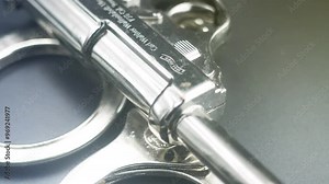 A gun lies on a table - the concept of crime. Spinning close up, the screensaver of a crime program. Raven steel reflections and glare. Gun with ammunition on dark background