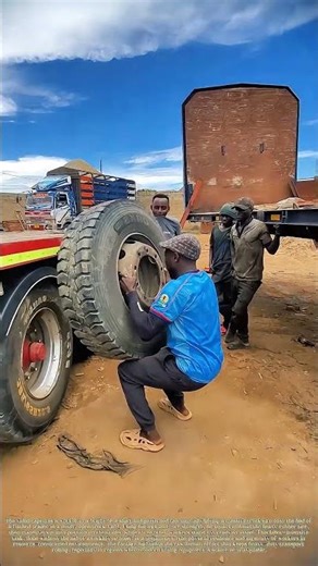 Lifting the Load: How a Worker Manually Hauls a Heavy Truck Tire onto a Trailer