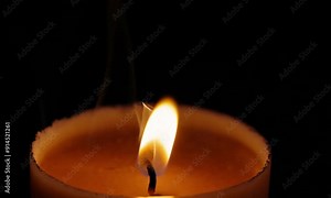 A single, flickering candle flame in a dark setting. The gentle movement of the flame creates a calming effect, Static close-up shot Stock Video