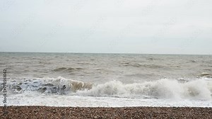 Angry waves crashing onto a pebbled beach in southern England