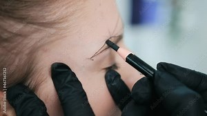 Permanent makeup master drawing right shape of eyebrows for model preparing for microblading