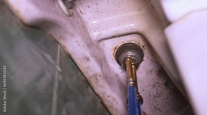 Connecting faucet to water supply using flexible braided hoses, plumber pulls hose into faucet . Connecting tap to water supply with braided hose. Connection to home water system.