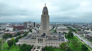 Nebraska state capitol building in downtown Lincoln, NE. Aerial orbit of tall government building on cloudy summer day.