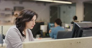 Businesswoman executive working at computer using device connected to global data in busy corporate office
