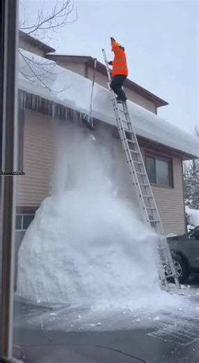 Worker Falls From Icy Ladder, Van Damaged Below ❄️🏠 Buffalo, New York — Monday, January 27, 2025 Smartphone footage filmed from a neighbor’s window shows a construction worker positioned high on a ladder clearing heavy snow from a roof. The video opens at the exact moment the ladder kicks out from under him on the icy ground, sending the worker falling roughly 15 feet. He drops directly into a large, soft pile of snow accumulated below, disappearing into the white powder as the ladder crashes d