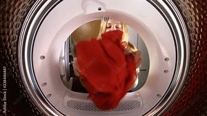 Funny little girl, her mother and father loading the their clothes and toys to washing machine. View from the inside of washing machine. Slow motion