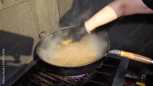 Cooking spaghetti in a large wok with boiling water in the kitchen preparing pasta meal