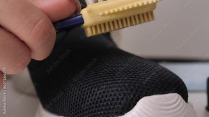Cleaning a sneaker with a shoe care brush. close-up slow motion