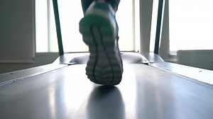 Woman running on treadmill in gym, slow motion