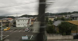 Train ride in rural Japan through a small town village by a slow local train
