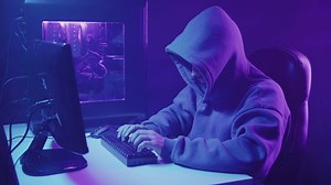 A guy in a hood typing on a computer. Hacker attack.