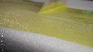 Epoxy resin being spread out on a foam board. surfboard glassing process. Smoothly applying yellow paint on a white surface. Stock Video