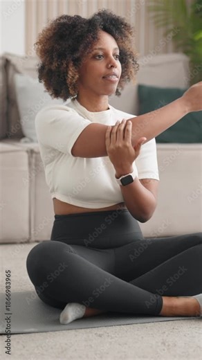 Slender woman doing stretching exercises for body flexibility, home fitness. African american female person practicing yoga and gymnastics for good body shape and feeling, sport activity in apartment