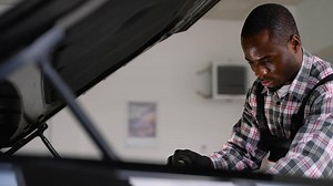 Focused auto mechanic repairing car engine in workshop