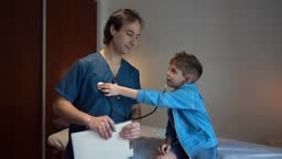 Boy playing with stethoscope with doctor in medical office