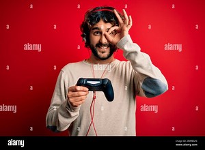 Young gamer man with curly hair and beard playing video game using joystick and headphones with happy face smiling doing ok sign with hand on eye look Stock Photo - Alamy