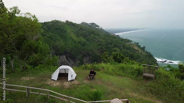 Aerial view drone camera 4k A man camping in a Hills and cliffs bordering the seaside and beaches with beautiful waves in Bukit jerit Kebumen central java Indonesia