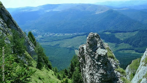 Limestone peaks of the Ciucas Mountains of Romania , part of the East European Carpathian range , with widespread coniferous forest and inhabited valley.