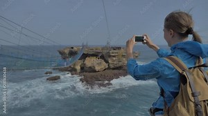 Woman take a picture with mobile phone at suspension bridge on Timang beach, Java island, Indonesia, Static Handled shot, No Color Grading