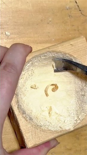 making a round hole in a square wooden block using a sharp metal carving chisel tool right now