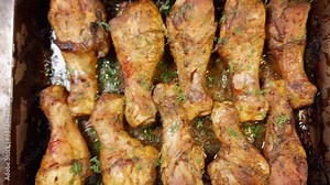 Baked chicken legs on metal oven-tray on rustic table