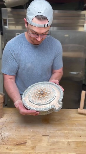 A manual stone mill for grinding grains. The stationary stone on the bottom is called the “Bed Stone” and the top stone which rotates is called the “Runner Stone”. Furrows are precisely chiseled into both stones and are separated by flat spaces called lands. A complete set of these furrows and lands are called harps and any given stone mill might have between six and ten harps. Look closely at the video and you will see that this small mill has 6 harps. The graduated nature of the furrows in the