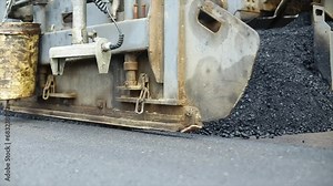 Compressing, compacting, leveling and smoothing the asphalt road surface using a Asphalt Paver Finisher. Process of asphalting road construction infrastructure