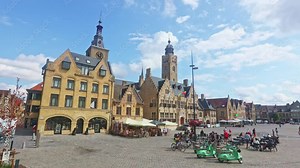 DIKSMUIDE, BELGIUM - AUGUST 5, 2022: Scenic view of summer cityscape of Diksmuide overlooking historic central square with City Hall and neighbouring Saint Nicolas Church on sunny day