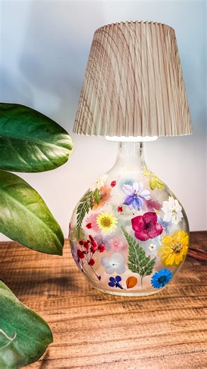 Dominique | Well Traveled Child on Instagram: "🌺instructions/products below!🌺 1. Find a bottle you want to use, flat surfaces work best. 2. Soaking warm water for easy label removal. 3. When fully dried use mod podge on small sections and apply flowers. Doing small sections works better because mod podge drives very quickly. 4. Once all the flowers have been applied, Add another layer of mod podge on top. 5. I used a Bottle top, you can also add fairy lights and thrift, acute lampshade, or a p