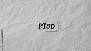 Crumpled piece of paper with letters PTSD on a crumpled white paper background.