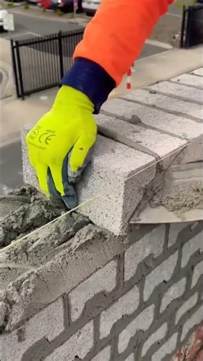 Arranging fresh concrete blocks carefully to build a strong, straight, and durable wall foundation