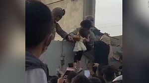 Afghan man hands child over wall to soldier at Kabul airport