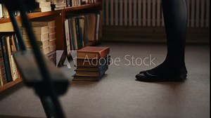 Legs of girl that stands on the books trying to reach upper shelves in the library.