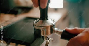 Barista presses ground coffee using tamper