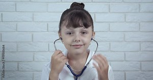Child play with stethoscope. A little girl want to make a doctor wark and puts on her stethoscope. A concept of choising of future profession.