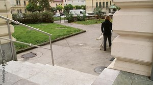 Visually impaired woman walking down the stairs with the help of her guide dog, rear view. Visual disability and independent lifestyles concept.