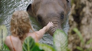 woman playing with elephant in zoo having fun in pool in tropical sanctuary