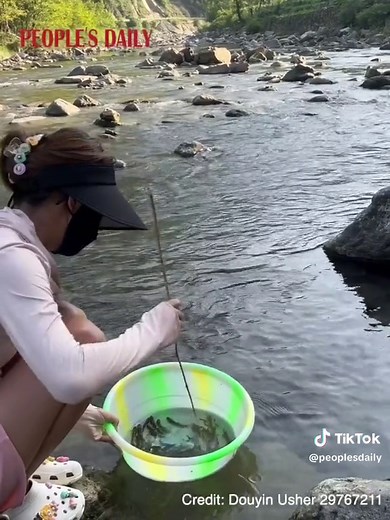 A Chinese woman made fishing look easy as she caught fish after fish with just a small tree branch. #China #chinesetiktok