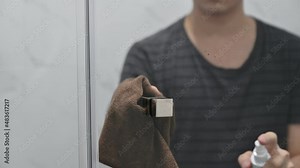 Man cleaning spray cleaner with cloth wiping on glass window