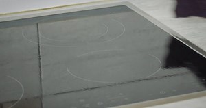 Cleaning induction electric stove at kitchen countertop. close up