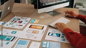 Excellent startup company employee presenting user interface prototype for mobile application to smart co-worker in office workspace. UX UI designer praising function of icon design on paper. Synergic