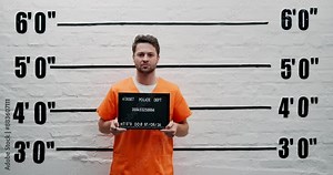 Man, criminal and suspect with sign for arrest, mugshot or violation in prison for questioning. Portrait of male person or thief with orange clothing, billboard or number for jail photo or picture
