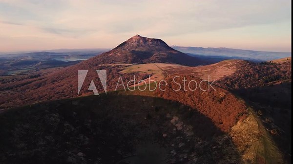drone shot flying over puy pariou and revealing the Puy de Dome in the background at sunrise, Clermont Ferrand, Auvergne, France