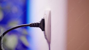Plug in and plug out of electric outlet thick black cable close-up 4K
