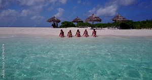 group of 5 beautiful women in bikinis sunbathing and chatting on white sand beach, jamaica