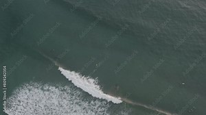 surfer catches wave down scale