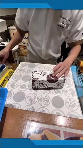 Wrapping a package neatly with patterned paper using precise folding techniques #giftwrapping