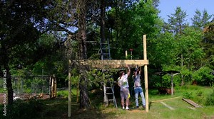 Men working on framing to support zip line starting platform and future tree house.